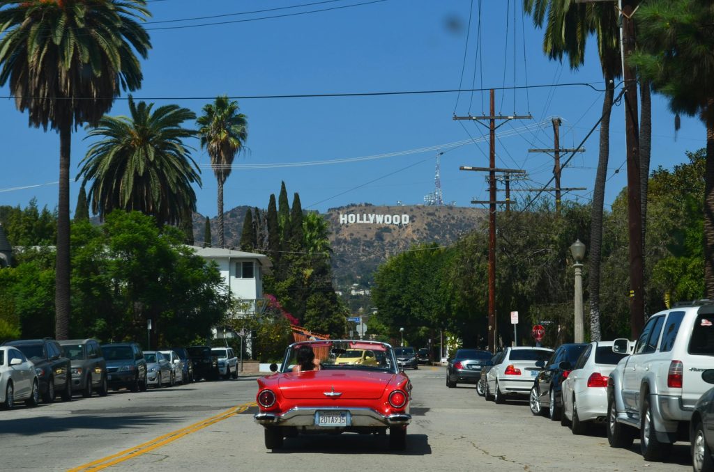 Red-convertible-driving-toward-Hollywood-the-land-of-filmmaking.