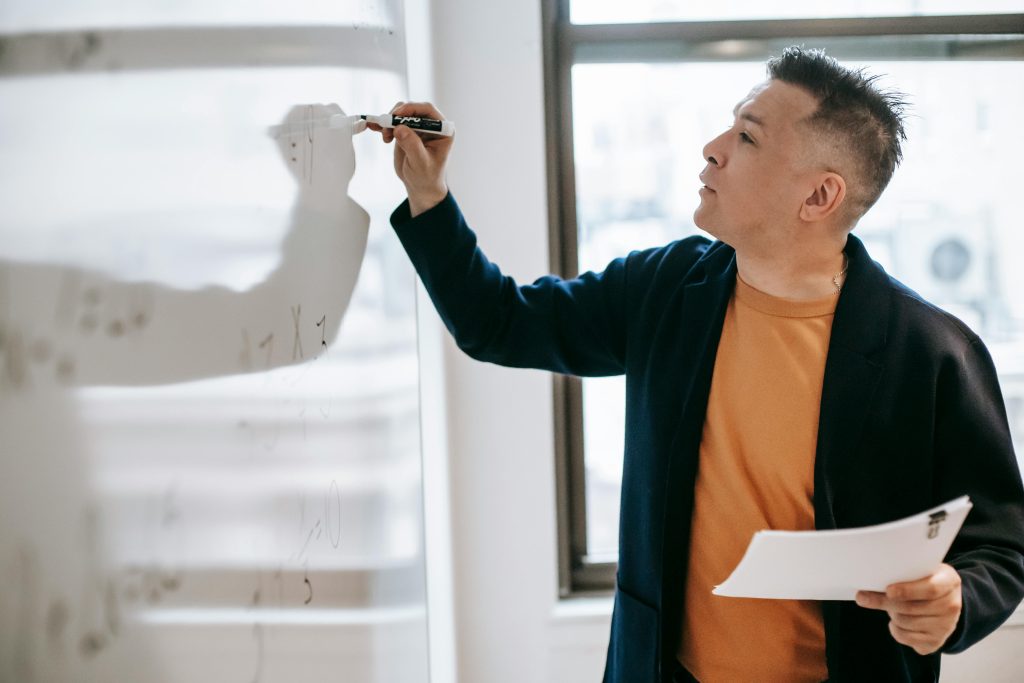 profile-of-male-teacher-in-black-blazer-writing-on-a-whiteboard