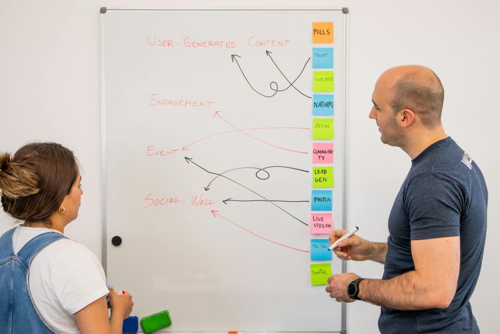 Two-colleagues-at-whiteboard-working-on-marketing-strategy.
