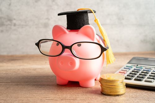 Pigging bank wearing eyeglass with with coins and calculator