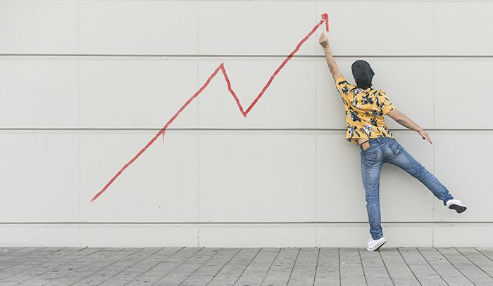 Digital composite of young man drawing a line graph at a wall
