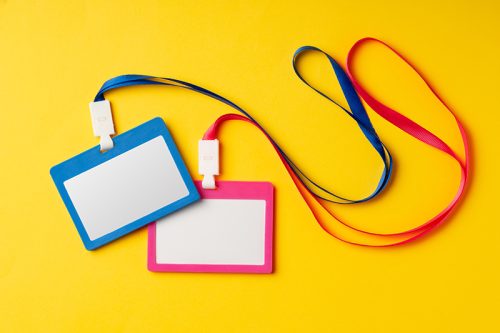 Colored blank nametags on strings on yellow background