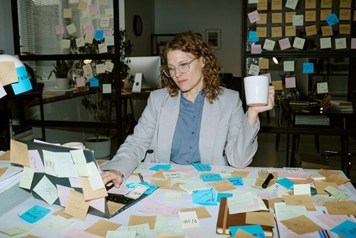 Young woman working at desk surrounded by sticky notes